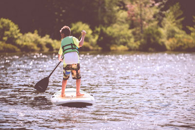 Мальчик плывет на плоту по озеру